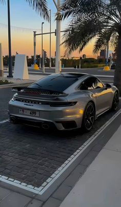 a silver sports car is parked on the side of the road near some palm trees