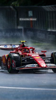 a red race car driving on a wet road with water spraying from it's tires