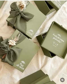 four green boxes with bows on them sitting on a bed