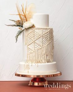 a white and gold wedding cake with feathers on top