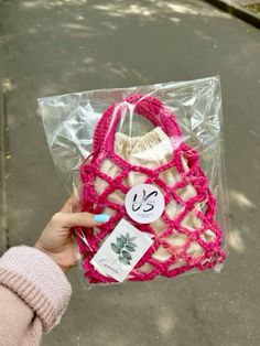 a hand holding a pink and white purse