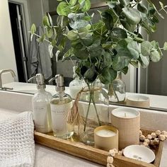 a wooden tray with candles, soaps and flowers on it in front of a mirror