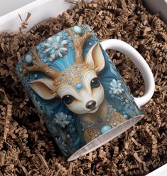 a ceramic mug with a deer head painted on it sitting in some wood shavings