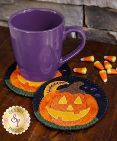 two halloween coasters on a table with candy in front of them and a purple mug