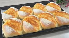 bread rolls on a black tray with powdered sugar