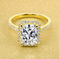 an engagement ring with a cushion cut diamond surrounded by round brilliant diamonds on a gold background