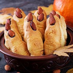 some almonds are on top of rolls in a brown bowl next to an orange pumpkin