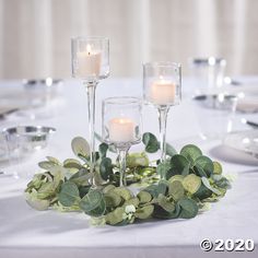 candles are lit on the table with greenery