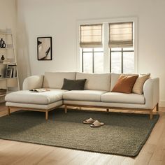 a white couch sitting on top of a wooden floor in a living room next to a window