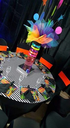 the table is decorated with colorful paper flowers and streamers on black tables cloths