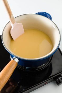 a wooden spoon in a pot on top of an electric burner with liquid inside