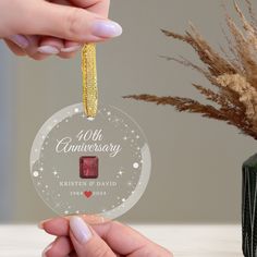 a person holding a glass ornament with the words, forty anniversary on it