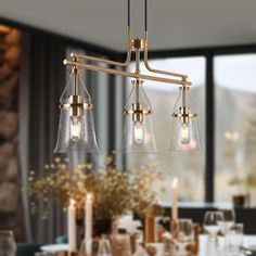 a chandelier hanging over a dining room table with wine glasses and candles on it