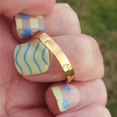 a hand holding a yellow and blue striped ring with flowers on the outside of it