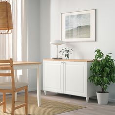 a room with a table, chair and potted plant on the floor next to it