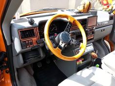 the interior of an orange and black car with steering wheel, dash board, radio, and other accessories