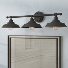 three light bathroom vanity fixture in an old - fashioned style with antique brass fixtures and black shades