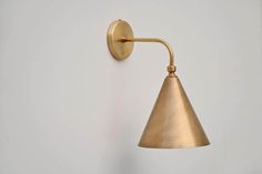 a brass wall light on a white wall with no one around it and the lamp is dimmed