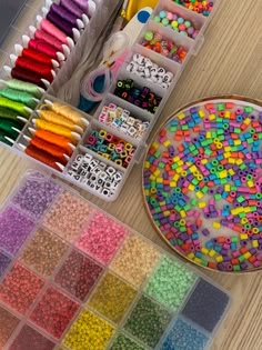 there are many different colors of beads in the box and on the table next to each other