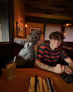 two people sitting at a table with remote controls