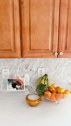 a bowl full of fruit sitting on top of a kitchen counter next to wooden cabinets