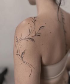 the back of a woman's shoulder with tattoos on it