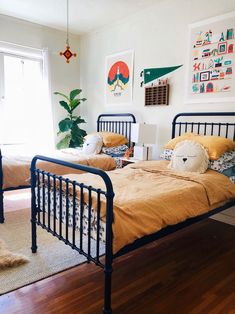 two twin sized beds in a bedroom with wood flooring and artwork on the wall