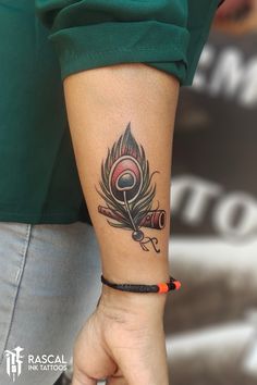 a woman's arm with a tattoo on it that has a feather and a telescope