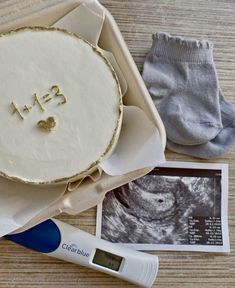 a birth cake in a box next to a pair of socks and a thermometer