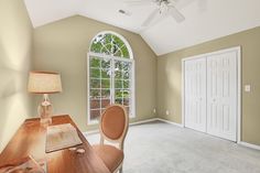 an empty room with a desk, chair and large window in the middle of it