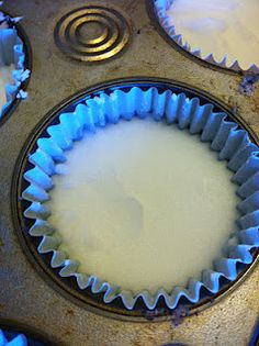 the inside of a cupcake pan with white icing on it and blue muffin tins next to it