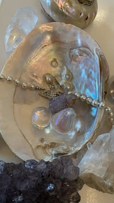 an assortment of pearls and other items on a white plate with black rocks in the background