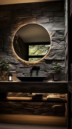 a bathroom with stone walls and a round mirror on the wall, along with a black sink