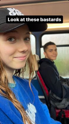 a young woman sitting in the back seat of a bus with a man behind her