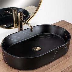 a black oval sink sitting on top of a wooden counter