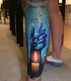 a person with a tattoo on their leg holding a candle