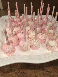 there are many pink and white candies in the tray on the table with candy sticks sticking out of them