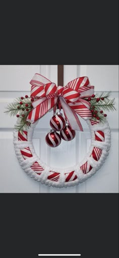 a red and white wreath with candy canes hanging from the front door, decorated with christmas decorations