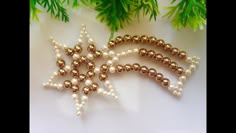 three beaded christmas ornaments are sitting on a table next to some green leaves and pine branches