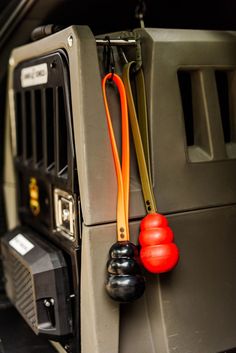 an orange handle is attached to the side of a gray vehicle with other items hanging on it