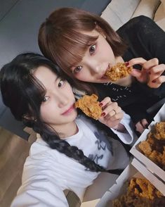 two young women eating food from boxes on the floor