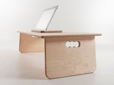 a laptop computer sitting on top of a wooden desk with a hole in the side