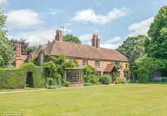 an old brick house with ivy growing on the roof and windows, surrounded by lush green grass