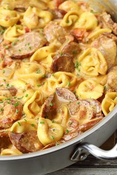 a pot filled with pasta and meat covered in sauce on top of a wooden table