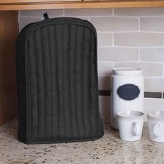 a kitchen counter with two mugs and an oven mitt