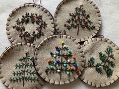 four embroidered christmas ornaments on a white surface