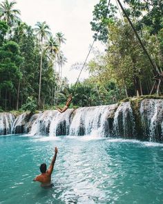 a man is in the water with his hands up and another person holding on to him