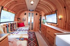 the interior of an rv with wood paneling and colorful bedspreads on each side