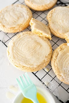 several cookies on a cooling rack next to a bowl of oil