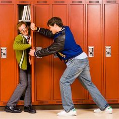 two young men in front of lockers trying to push each other